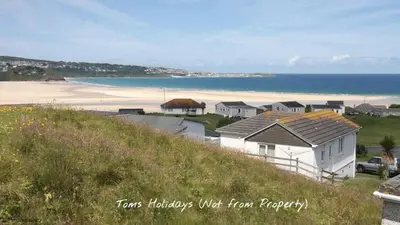 a house on a hill next to a beach at G05 Horizon G5, Riviere Towans in Hayle