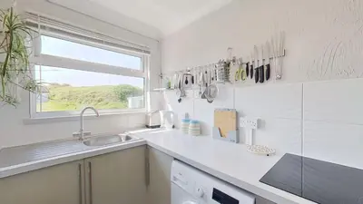 a white kitchen with a sink and a window at G05 Horizon G5, Riviere Towans in Hayle