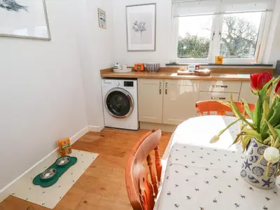 a kitchen with a table and a washing machine at Chilowan in Tintagel