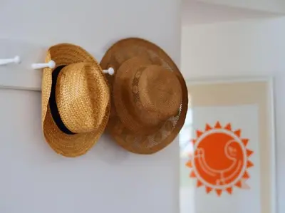 two straw hats are hanging on a wall at The little post house. A perfect village retreat, with stunning views. in Boscastle