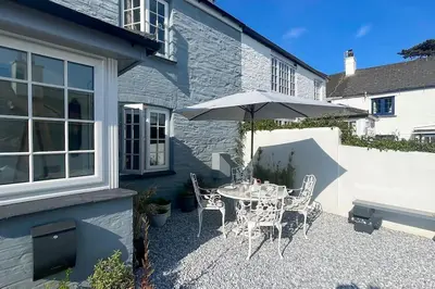a table and chairs with an umbrella on a patio at Luxury holiday cottage by the harbour in St Mawes in Saint Mawes