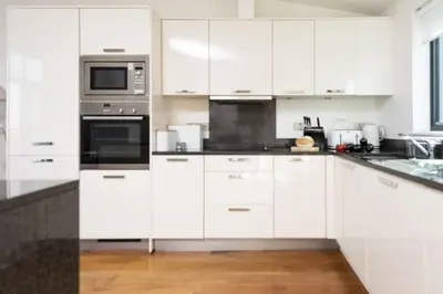 a white kitchen with white cabinets and appliances at Apartment 3 at Porthminster Mews in St Ives