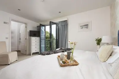 a white bedroom with a tray of flowers on a bed at Apartment 3 at Porthminster Mews in St Ives