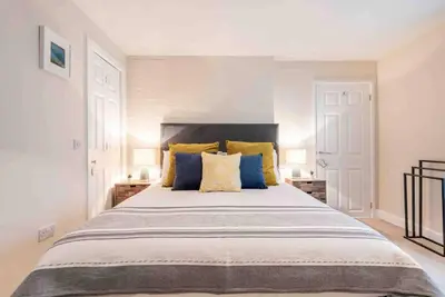a bedroom with a large bed with yellow and blue pillows at The Little Loft St Ives in St Ives