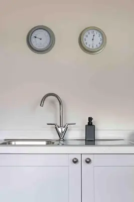 two clocks on the wall above a kitchen sink at The Little Loft St Ives in St Ives