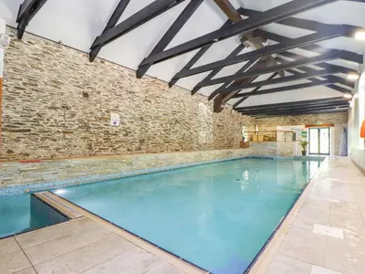 an indoor swimming pool with a brick wall at Trewince Manor Cottage in Truro