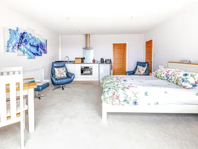 a bedroom with a bed and a desk and a kitchen at Greenside Studio in Penzance