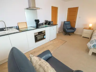 a living room with a couch and a kitchen at Greenside Studio in Penzance