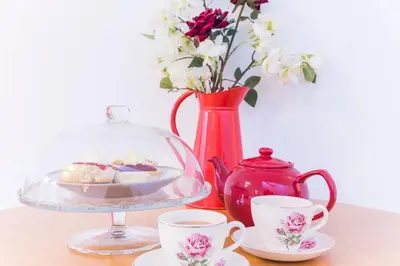 a table with a plate of cookies and a vase with flowers at Home from Home self catering for 2 in St Austell